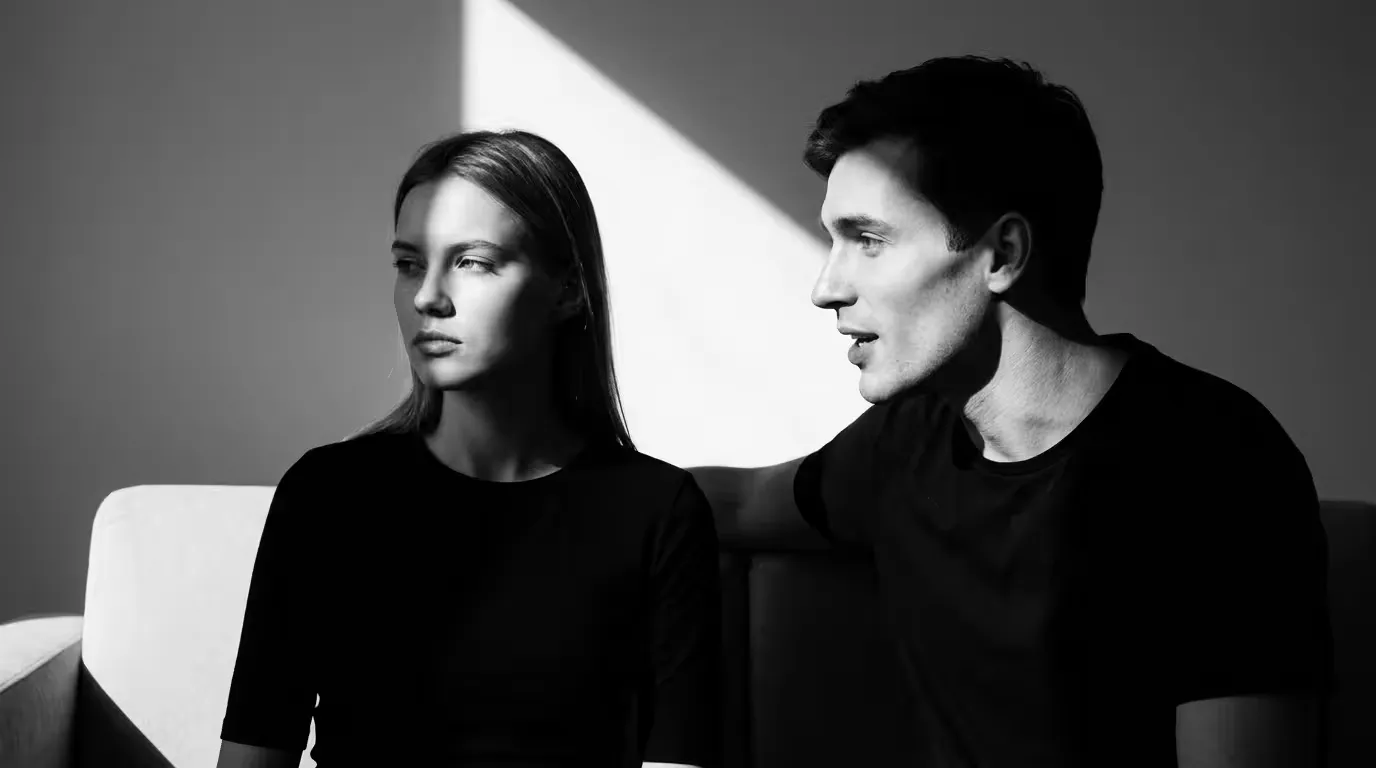 A woman looking directly ahead while a man beside her turns toward her, neither meeting the other’s eyes