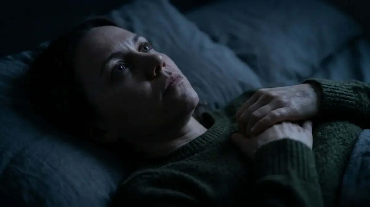 A woman lying awake in bed in the dark